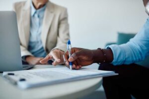 Homeowner reviews damage photos and claim documents with an adjuster inside a water-damaged room.